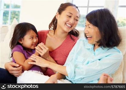 Grandmother Playing On Sofa With Granddaughter And Daughter