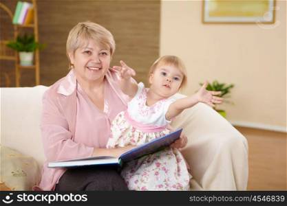 grandmother reading a book to her granddaghter at home