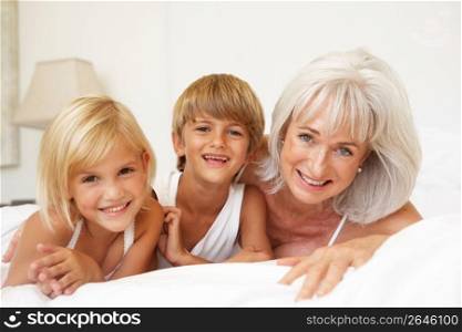 Grandmother Relaxing On Bed With Grandchildren