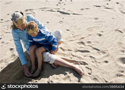 Grandmother sitting with grandson on laps on sand
