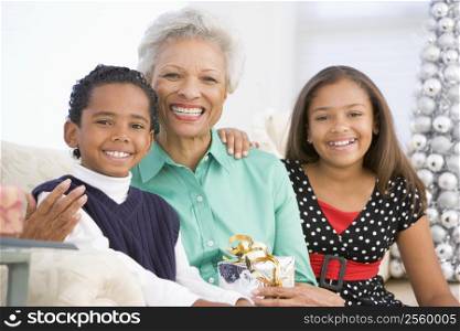Grandmother Sitting With Her Two Grandchildren,Holding A Christmas Gift