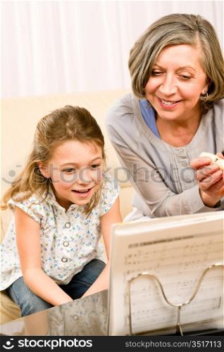 Grandmother teach young girl learn music notes play flute smiling