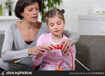 grandmother teaching granddaughter how to knit