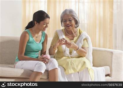 Grandmother teaching granddaughter how to knit