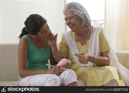 Grandmother teaching granddaughter how to knit