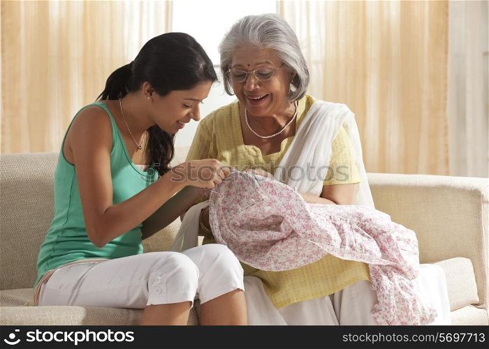 Grandmother teaching granddaughter how to sew