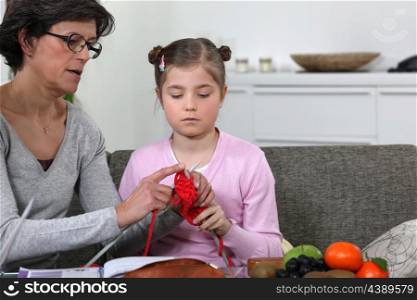 Grandmother teaching her granddaughter how to knit