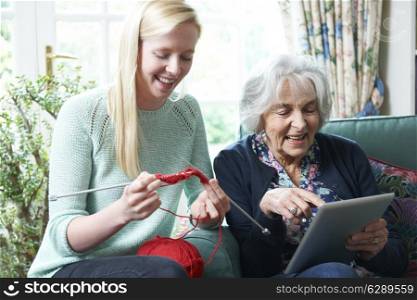 Grandmother Using Digital Tablet Whilst Granddaughter Knits