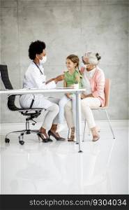 Grandmother with cute grandaughter black female doctor in the office