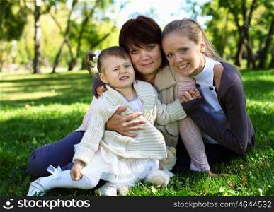 Grandmother with daughter and granddaghter in green summer park