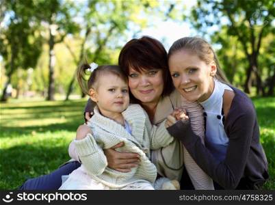 Grandmother with daughter and granddaghter in green summer park