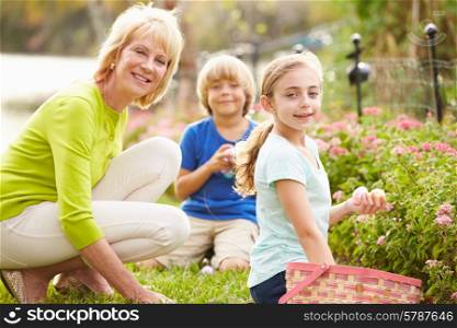 Grandmother With Grandchildren On Easter Egg Hunt In Garden