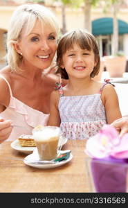 Grandmother With Granddaughter Enjoying Coffee And Cake In CafZ