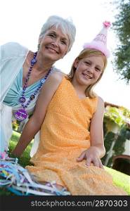 Grandmother with granddaughter in garden while birthday party