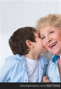 Grandmother with grandson having fun at home - whispering secrets