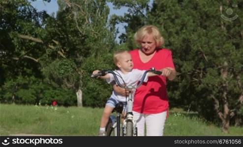 Grandmother with grandson having fun on bicycle in park