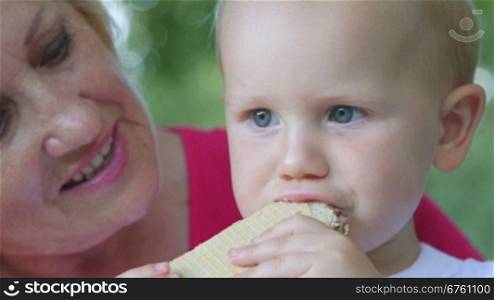 Grandmother with her grandchild eating waffles outdoors
