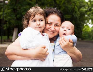 Grandmother with her grandchildren in a park. Family portraits