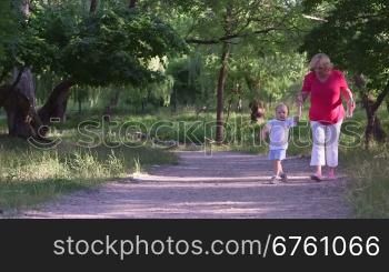 Grandmother with her grandson walking along the alley in summer park