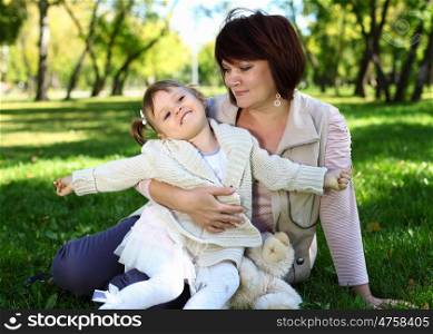 Grandmother with her little granddaghter in green summer park
