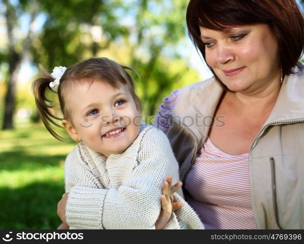 Grandmother with her little granddaghter in green summer park