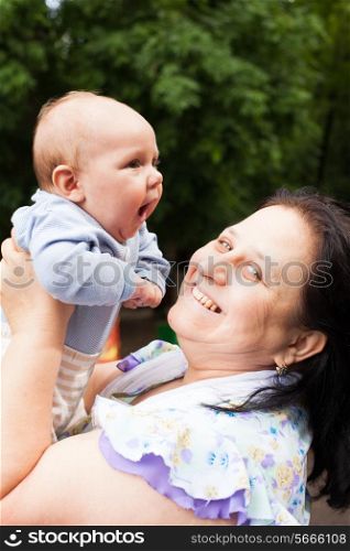 Grandmother with her little grandson in a park. Family portraits