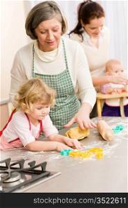 Grandmother with little girl prepare dough for baking cookies