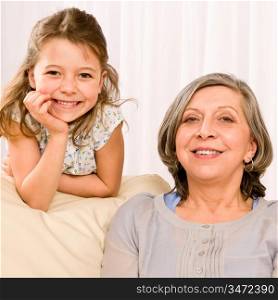 Grandmother with young girl smiling relax together on sofa