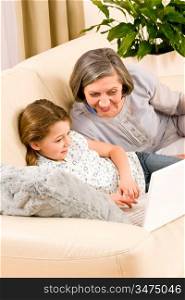 Grandmother with young girl use computer laptop happy together