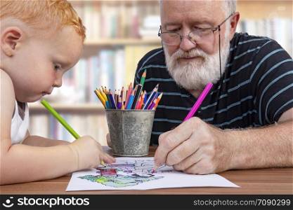 Grandpa working together and coloring on a drawing with his little grandson