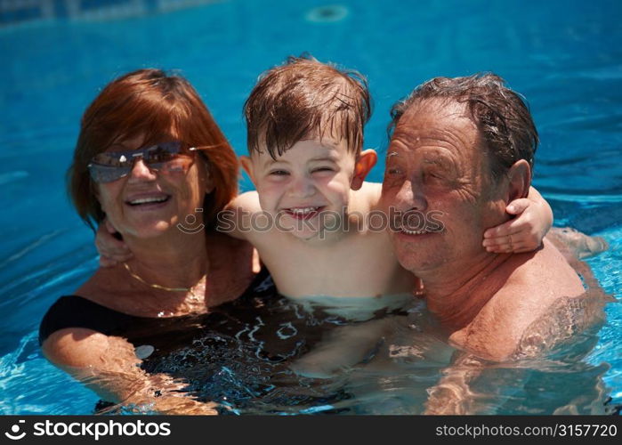 grandparents and child playing in swimming pool