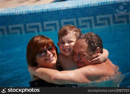 grandparents and child playing in swimming pool