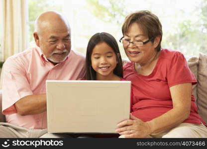 Grandparents And Grandaughter Using Laptop Computer At Home