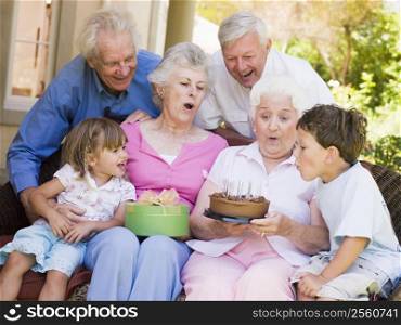 Grandparents and grandchildren on patio with cake and gift smiling