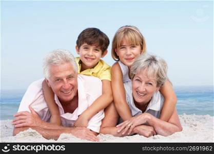 Grandparents And Grandchildren Relaxing On Beach Holiday