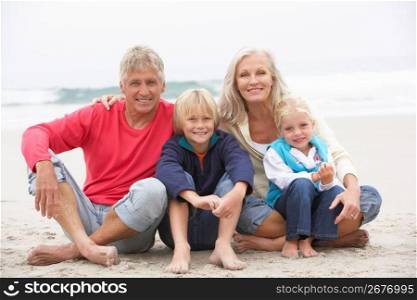 Grandparents And Grandchildren Sitting On Winter Beach Together