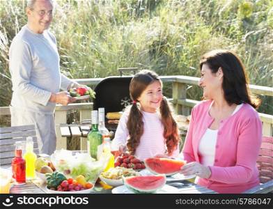 Grandparents And Granddaughter Having Outdoor Barbeque