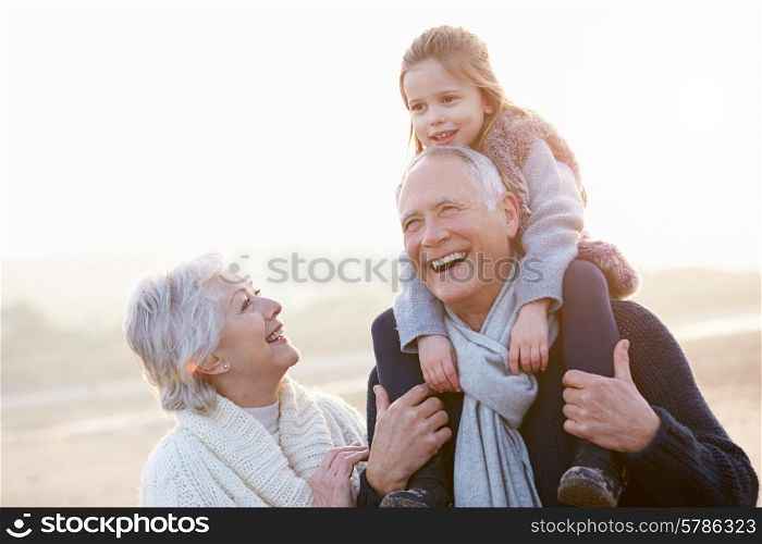 Grandparents And Granddaughter Walking On Winter Beach
