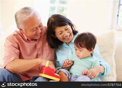 Grandparents And Grandson Playing With Toy Together