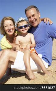 Grandparents And Grandson Sitting On Beach