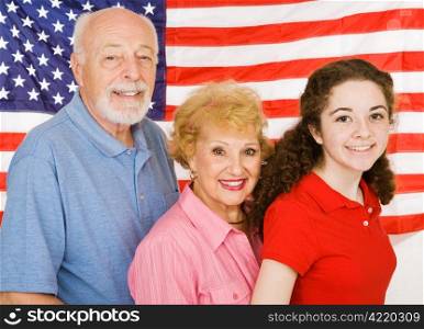 Grandparents and their granddaughter in front of an American Flag.