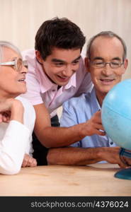 grandparents ant their grandson looking at a globe