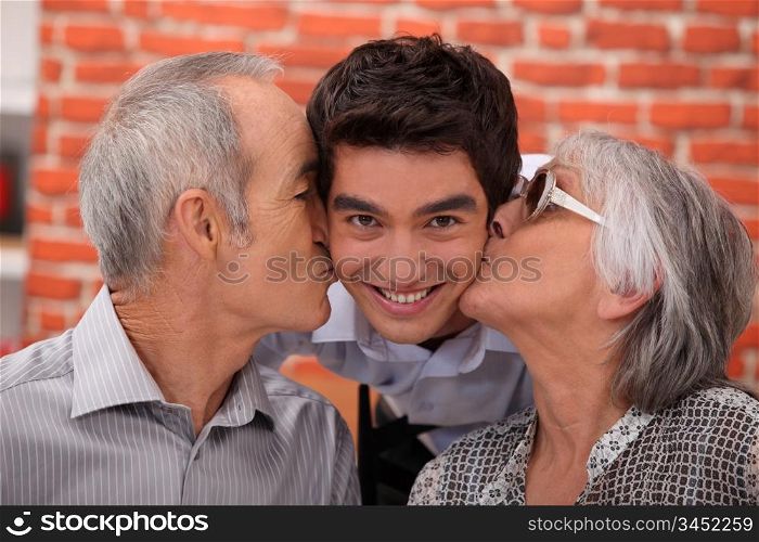 Grandparents kissing their adult grandson