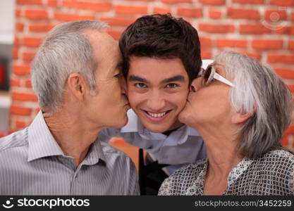 Grandparents kissing their adult grandson