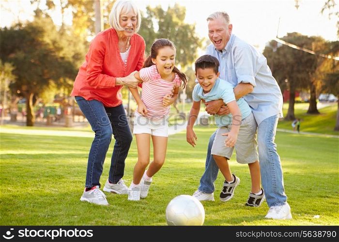 Grandparents Playing Soccer With Grandchildren In Park