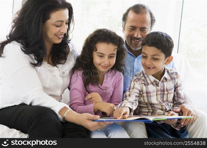 Grandparents sitting in living room reading with grandchildren smiling (high key)