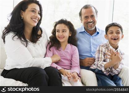 Grandparents sitting in living room with grandchildren smiling (high key)