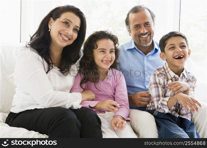 Grandparents sitting in living room with grandchildren smiling (high key)