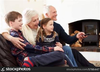 Grandparents Sitting On Sofa Watching TV With Grandchildren