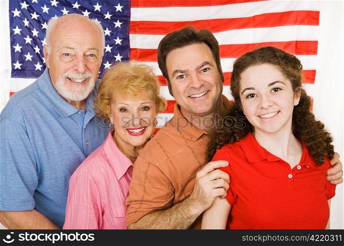 Grandparents, their adult child, and their granddaughter, posing in front of an American Flag.